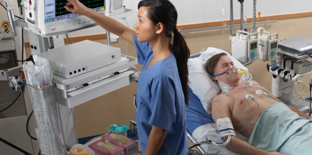 Clinician touching a monitor next to a male patient laying on a bed