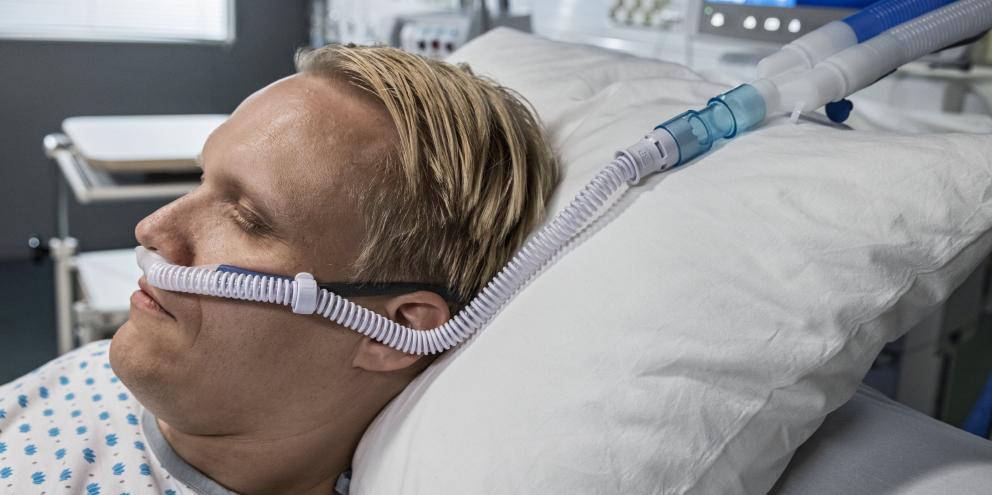 Male patient laying in bed with high-flow oxygen therapy