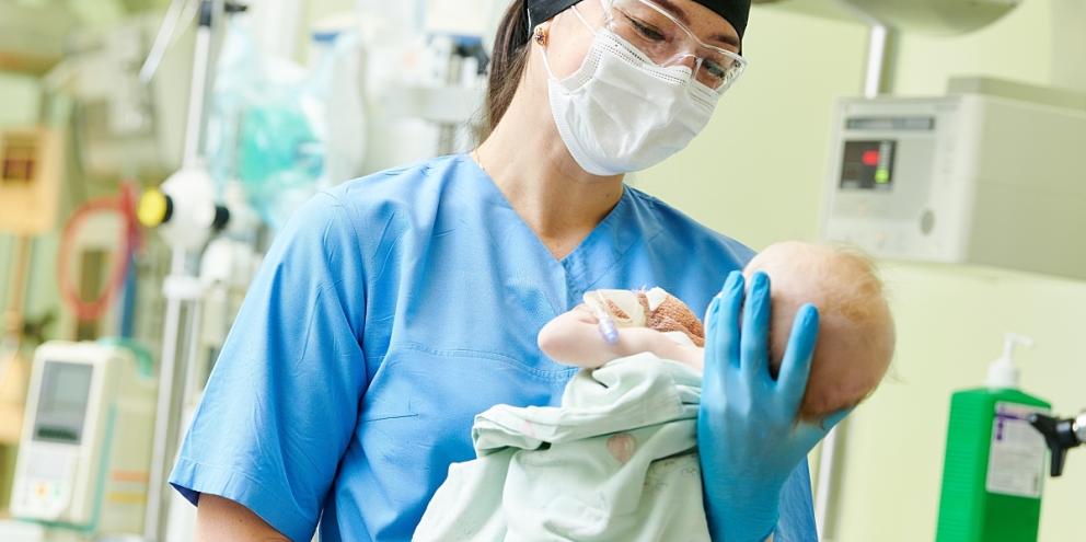 L&D nurse holding infant after delivery