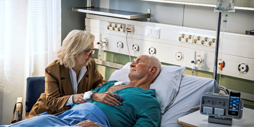 Patient laying on a bed wearing Portrait Mobile with his wife