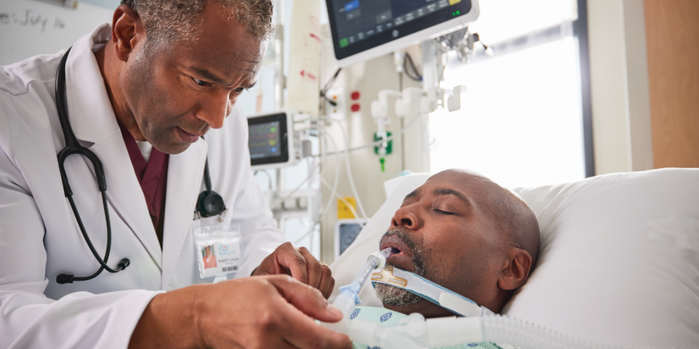 Male patient intubated in the ICU with a clinician besides him