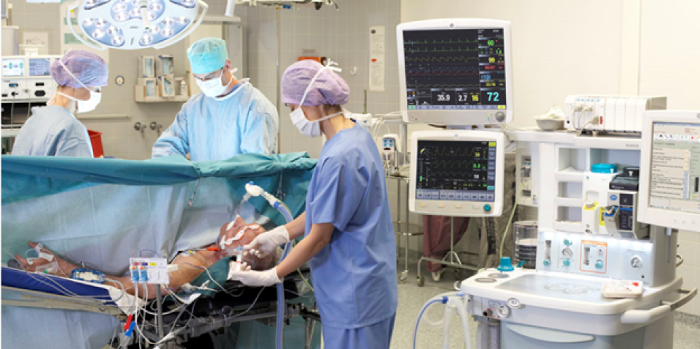 Three clinicians performing surgery on a patien