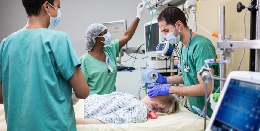 Three clinicians taking care of a patient in the ICU