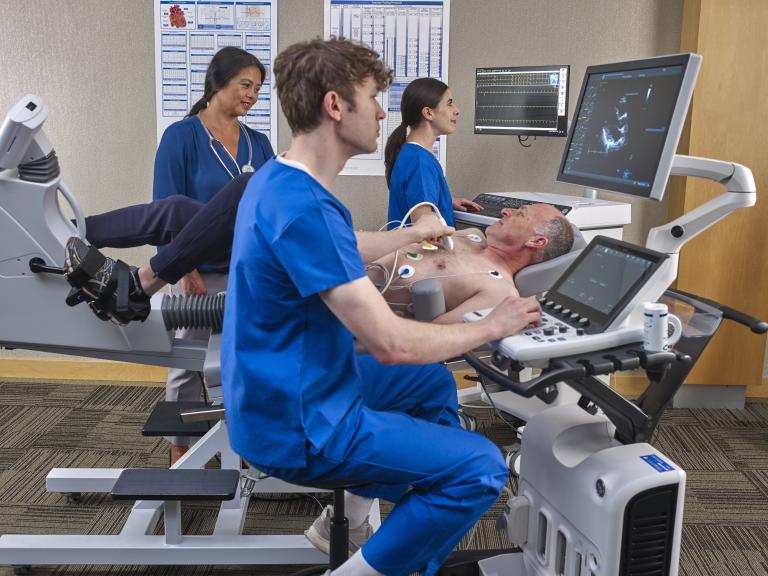 Clinicians performing an ultrasound and an ECG to a male patient