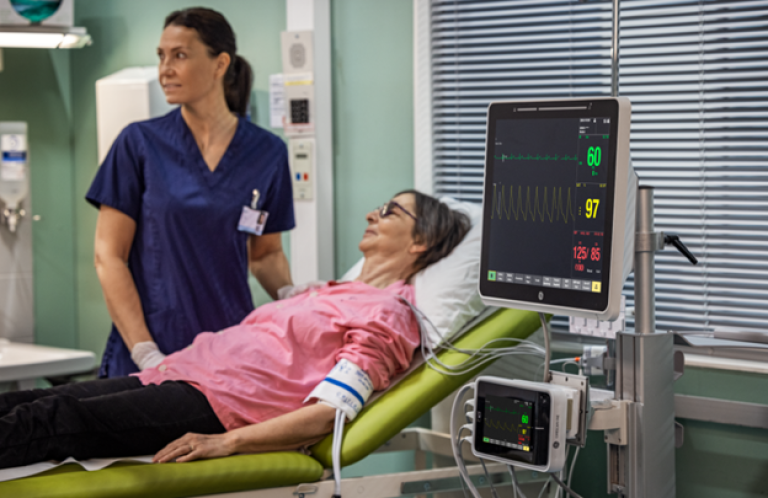 Female clinician standing near to a lying patient with Carescape CANVAS