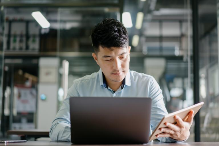 Biomedical engineer looking at his tablet and laptop