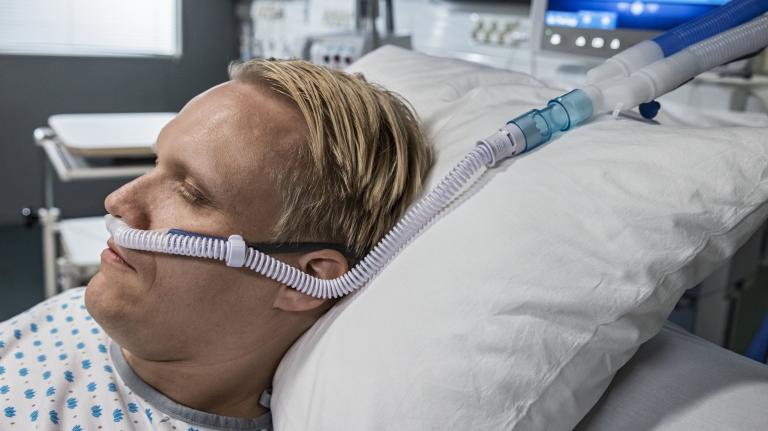 Male patient laying in bed with high-flow oxygen therapy