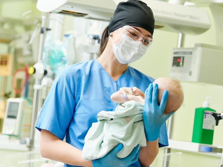 L&D nurse holding infant after delivery