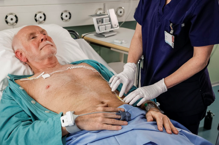 Patient laying on a bed wearing Portrait Mobile with a clinician beside him