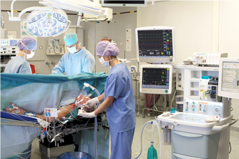 Three clinicians performing surgery on a patien