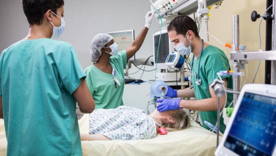 Three clinicians taking care of a patient in the ICU