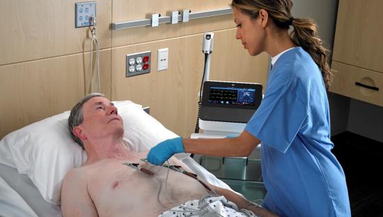 Female clinician setting ECG wires to male patient.