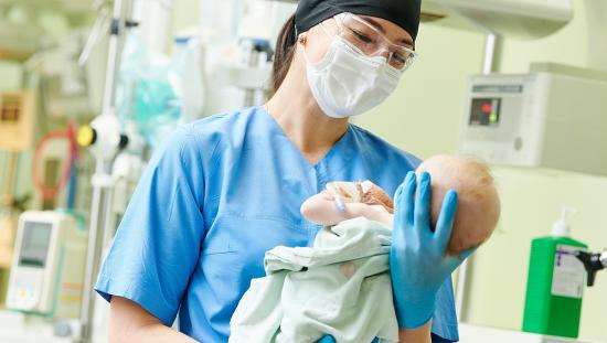 L&D nurse holding infant after delivery