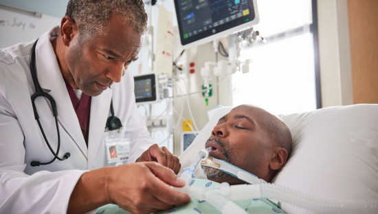 Male patient intubated in the ICU with a clinician besides him