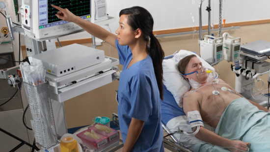 Clinician touching a monitor next to a male patient laying on a bed