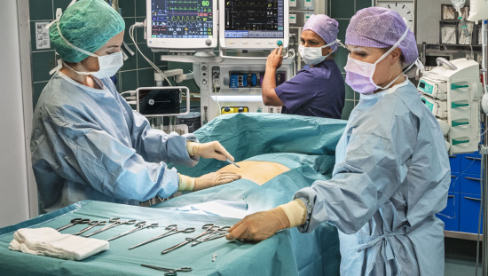 Three clinicians performing surgery in a patient in the OR
