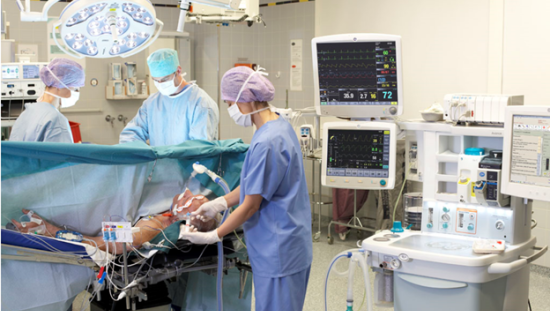 Three clinicians performing surgery on a patien