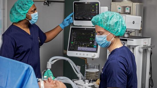Two clinicians in the operating room with an anesthetized patient